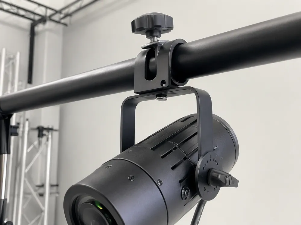 مشبك تثبيت عالمي لسبوت لايت DJ مركب على حامل T-bar بقطر 25mm-38mm يُظهر برغي إبهامي مع واشر مثبت وقفل إمالة بربع دورة